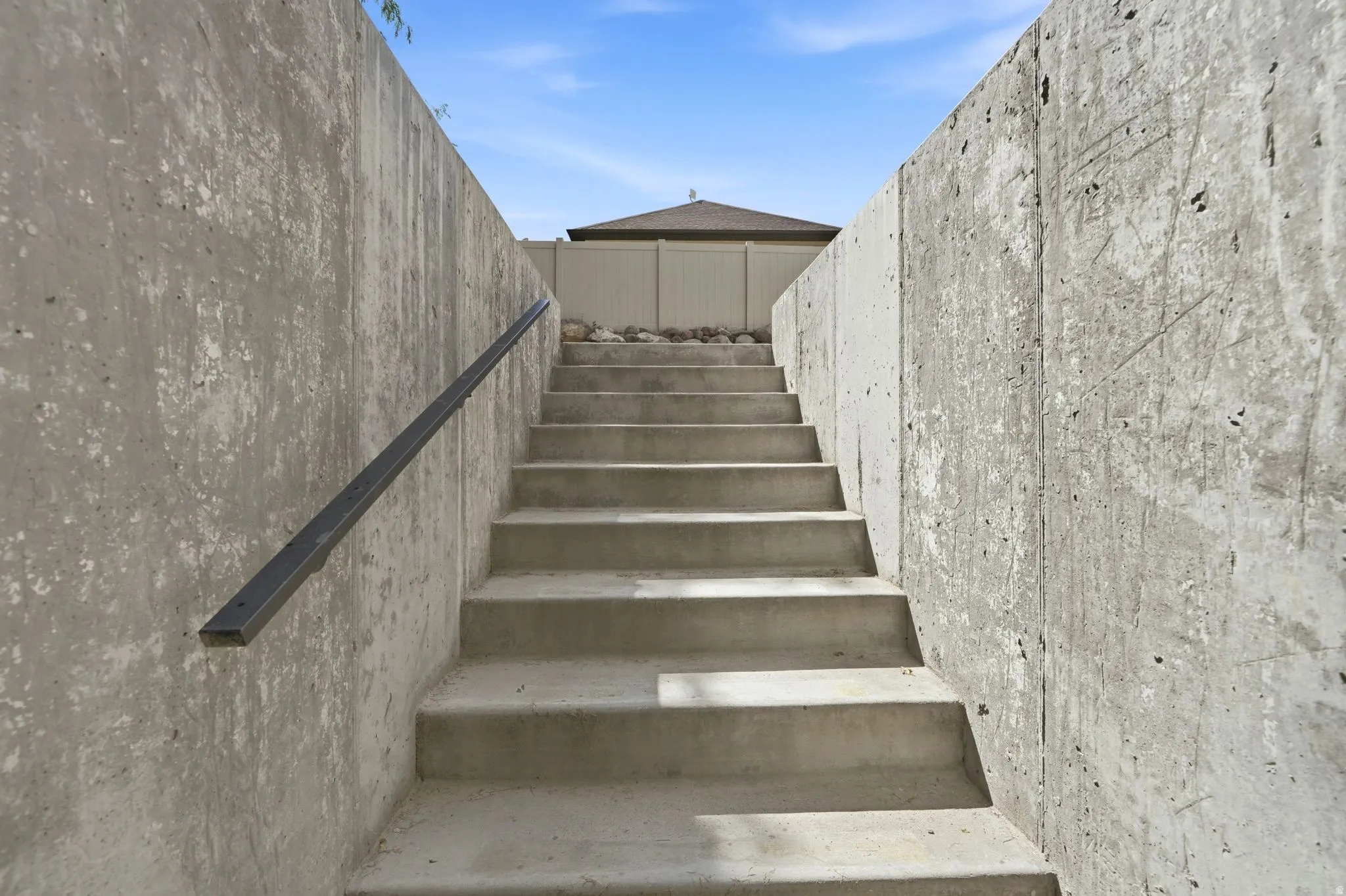 Concrete retaining walls with integrated concrete staircase and black metal handrail