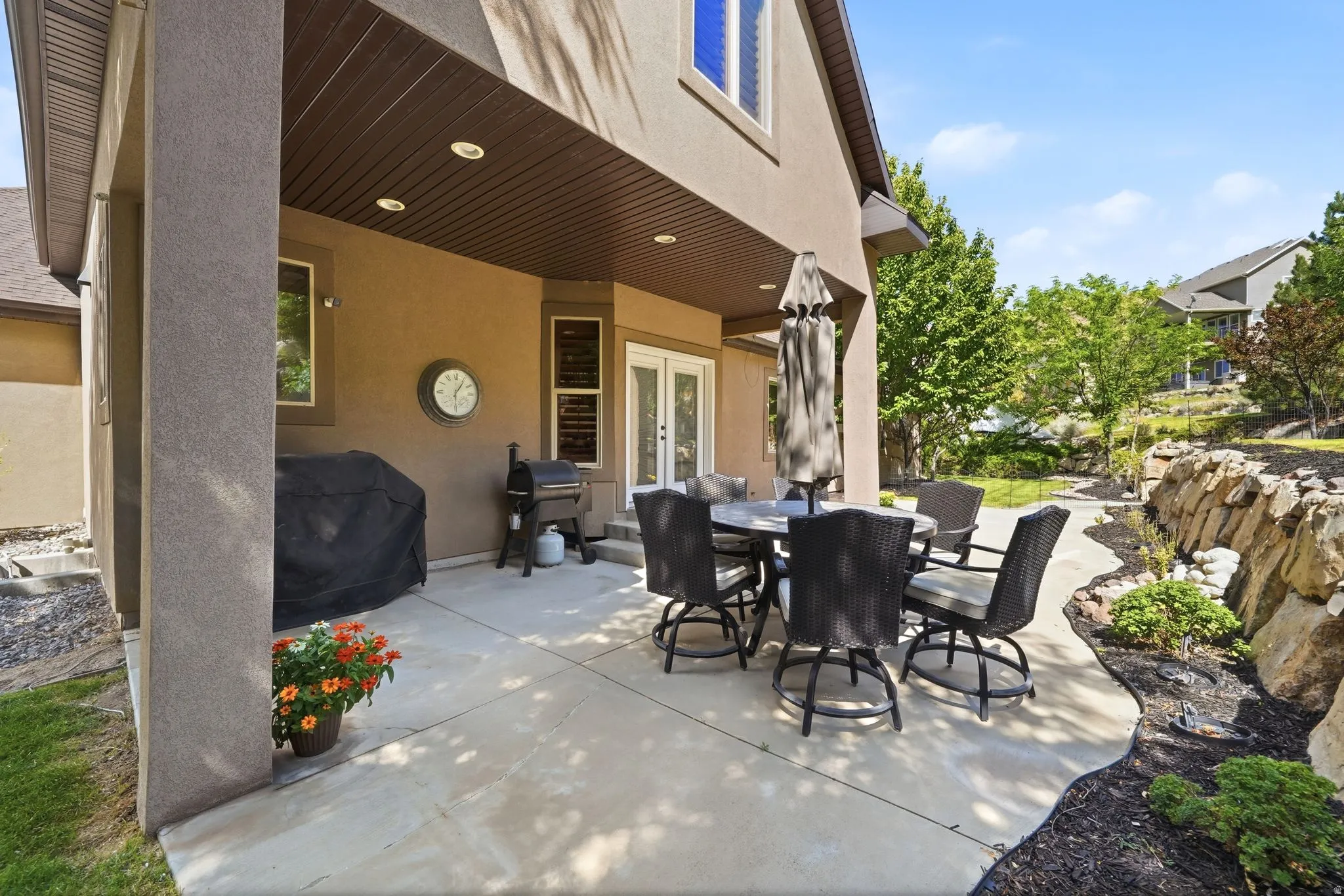 Covered patio with integrated recessed lighting, stone-finish flooring, and a ceiling fan