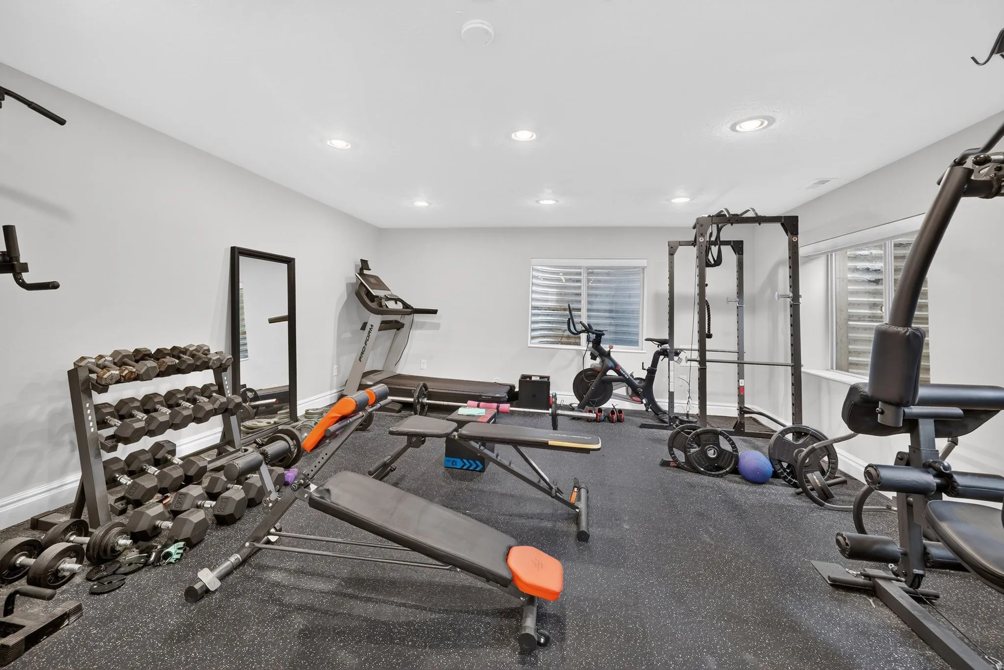 Dedicated fitness area featuring recessed lighting, durable rubber flooring, and multiple windows with privacy blinds