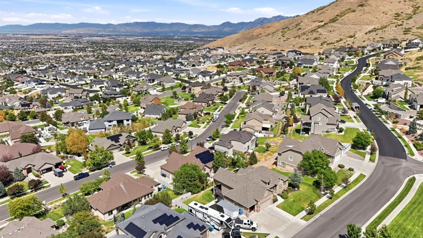 Expansive residential neighborhood with varied architectural styles, mature landscaping, and paved streets, set against a mountain backdrop