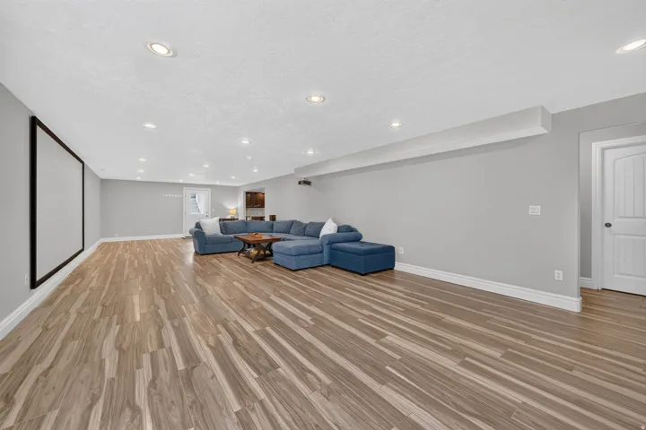 Spacious room with wood-finish flooring, recessed lighting, and a projection screen