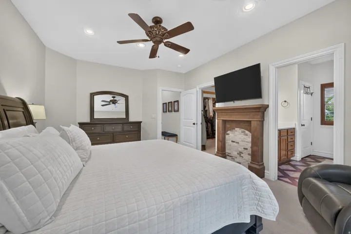 Recessed lighting, ceiling fan, wood-finish mantel with tiled surround, and direct access to an adjacent room