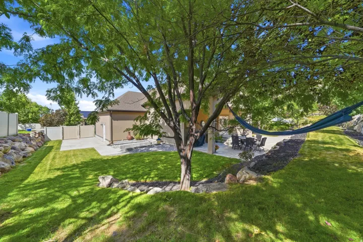Expansive lawn with mature trees and a paved patio area