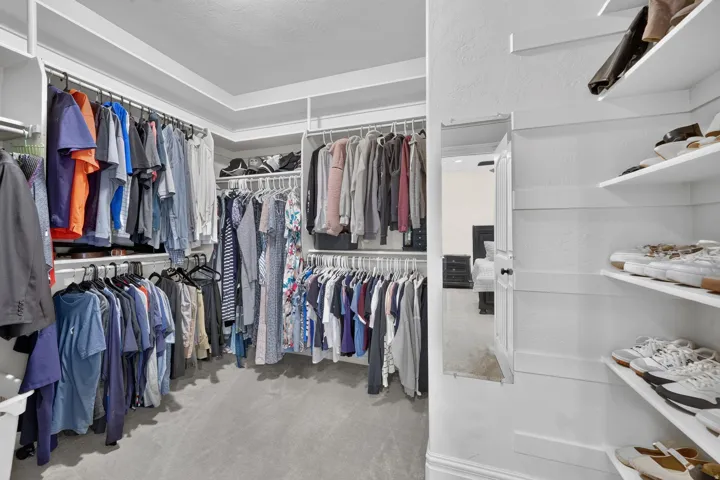 Walk-in closet featuring extensive built-in shelving, multiple hanging rods, and an integrated full-length mirror