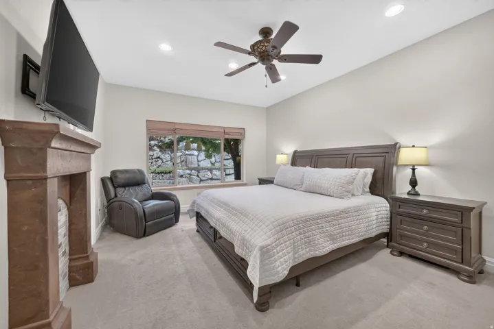 Recessed lighting, ceiling fan, carpet flooring, and a stone-clad fireplace