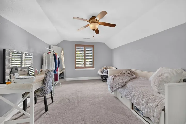 Vaulted ceiling, ceiling fan, wood-finish window shutters, window, and wall-to-wall carpeting