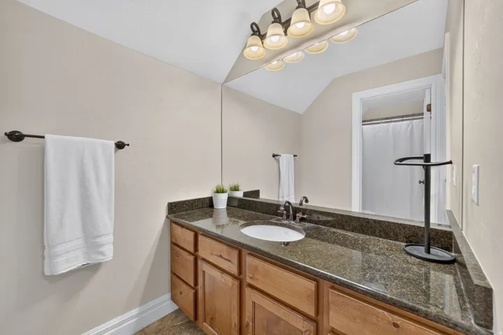 Wood-finish vanity with an integrated sink and dark countertop