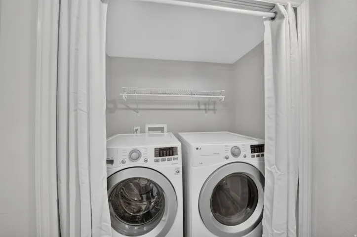 Dedicated laundry area with white front-load washer and dryer, accompanied by a wall-mounted wire shelf for storage
