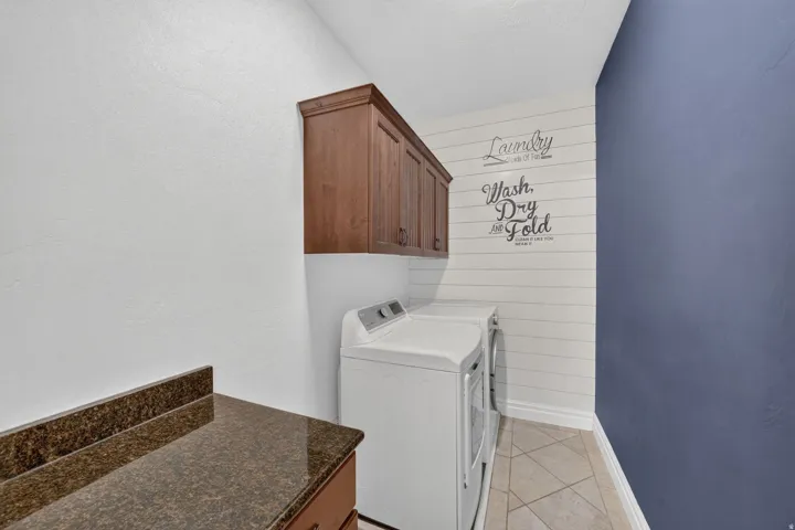 Utility space featuring granite-finish countertop, wood cabinetry, and tiled flooring
