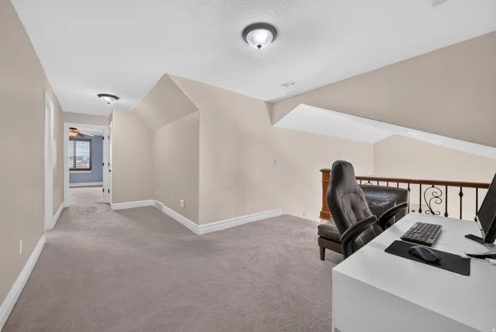 Carpeted loft space with a wrought iron and wood balustrade