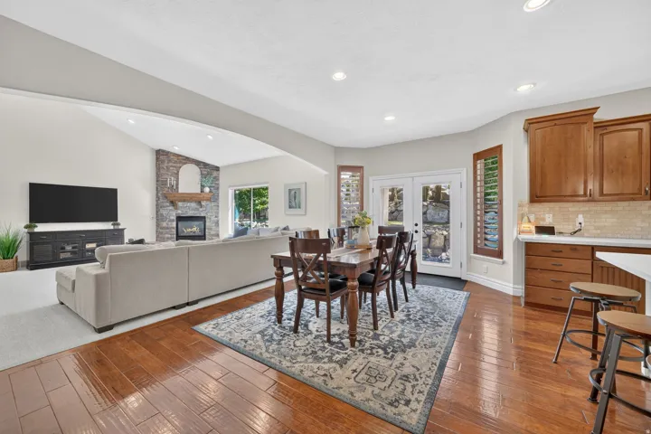 Open-concept living and dining area featuring warm wood-finish flooring, recessed ceiling lighting, and a neutral color palette