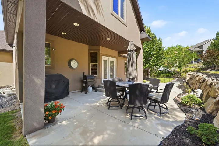 Covered patio with integrated recessed lighting, stone-finish flooring, and a ceiling fan