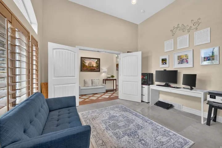 Vaulted ceiling featuring recessed lighting, wood-finish plantation shutters, double interior doors with arched top panels, and light-toned wall finishes
