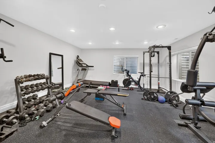 Dedicated fitness area featuring recessed lighting, durable rubber flooring, and multiple windows with privacy blinds