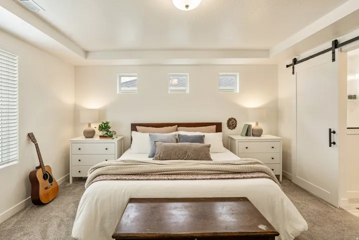 Recessed ceiling with central lighting fixture, three transom windows, a large window with blinds, and a barn door with black hardware