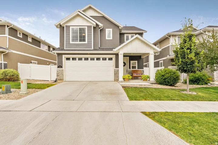 Two-story residence featuring a covered front porch, attached garage with square window inserts, and a concrete driveway