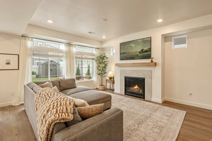 Recessed lighting, wood-finish flooring, full-light windows, built-in fireplace with tile surround, and a wood mantel