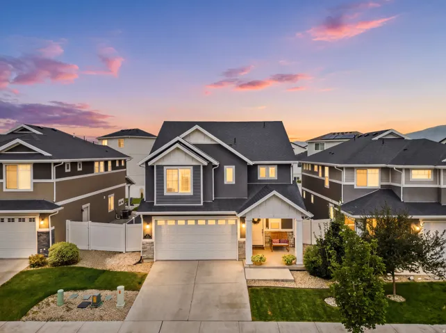 Contemporary exterior with dark siding and white trim, featuring an attached garage, covered front porch, and concrete driveway