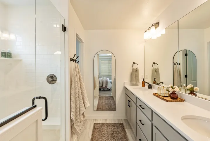 Dual basin vanity with an integrated countertop, extensive wall mirror, and modern light fixture