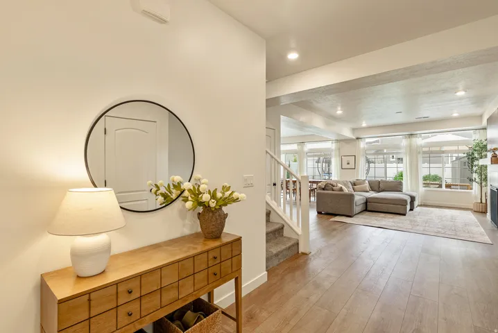Wood-finish flooring throughout, recessed ceiling lighting, and a white painted staircase with carpeted treads