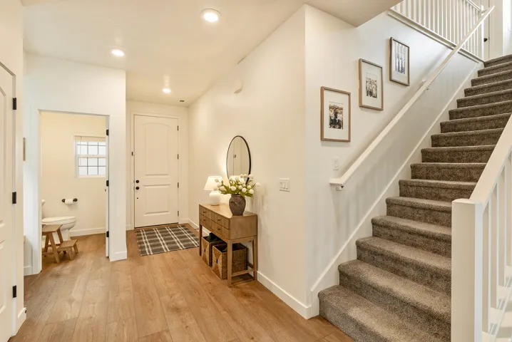 Recessed lighting, wood-finish flooring, white panel doors, and a carpeted staircase with white railings