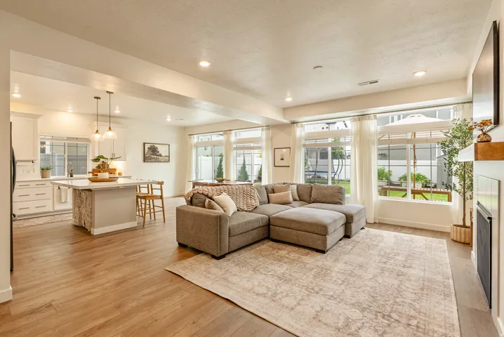 Open-concept living space featuring wood-finish flooring, recessed lighting, a built-in fireplace, and expansive windows