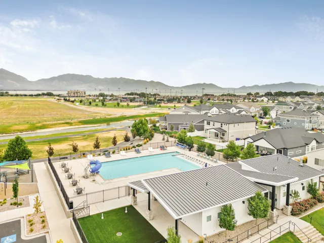 Community swimming pool, fenced recreation area, playground structure, mountain backdrop, and surrounding residential properties