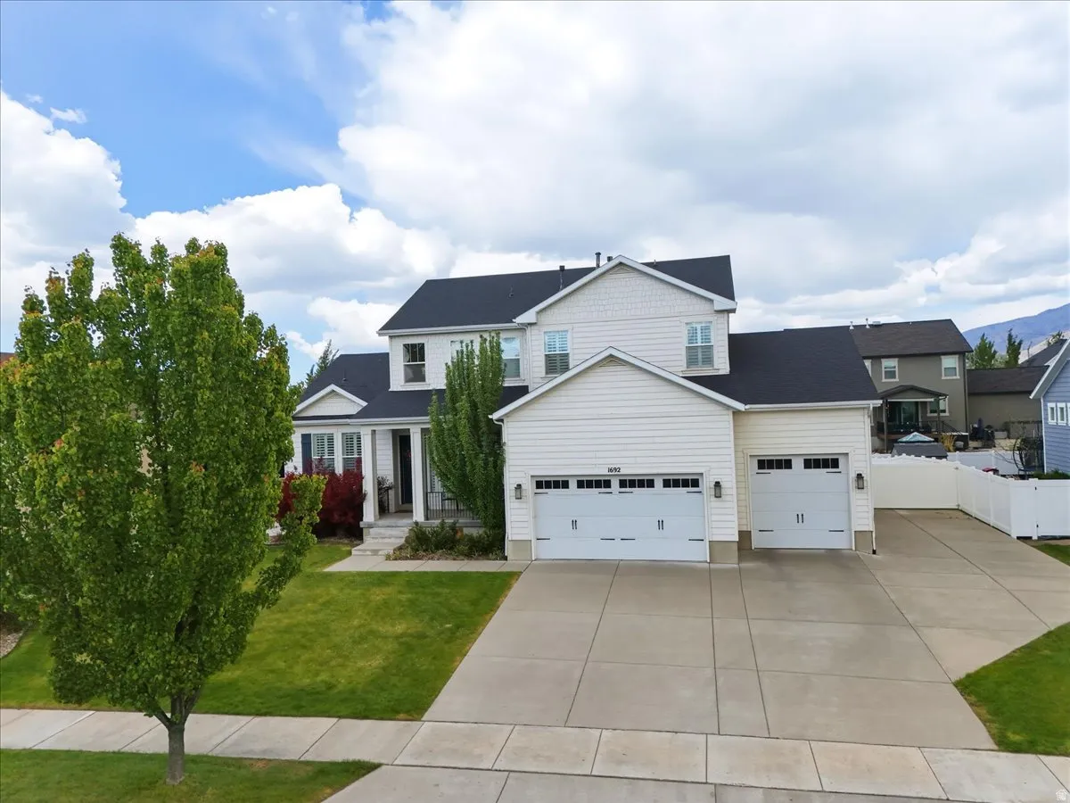Two-story residence with white siding, a dark shingle roof, and an attached two-car garage