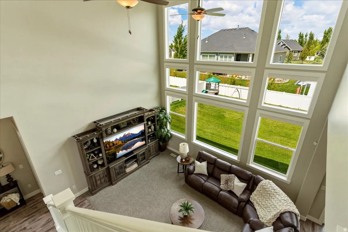 Two-story living area with large-format windows, vaulted ceiling, and ceiling fan
