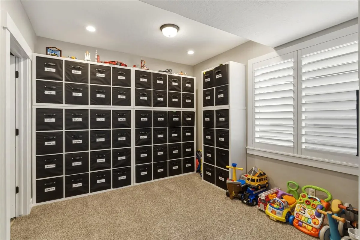 Built-in modular shelving, neutral carpet flooring, recessed lighting, and plantation shutters