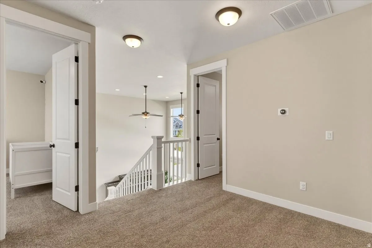 Carpeted landing with white balusters, overhead lighting, and interior doors with black hardware