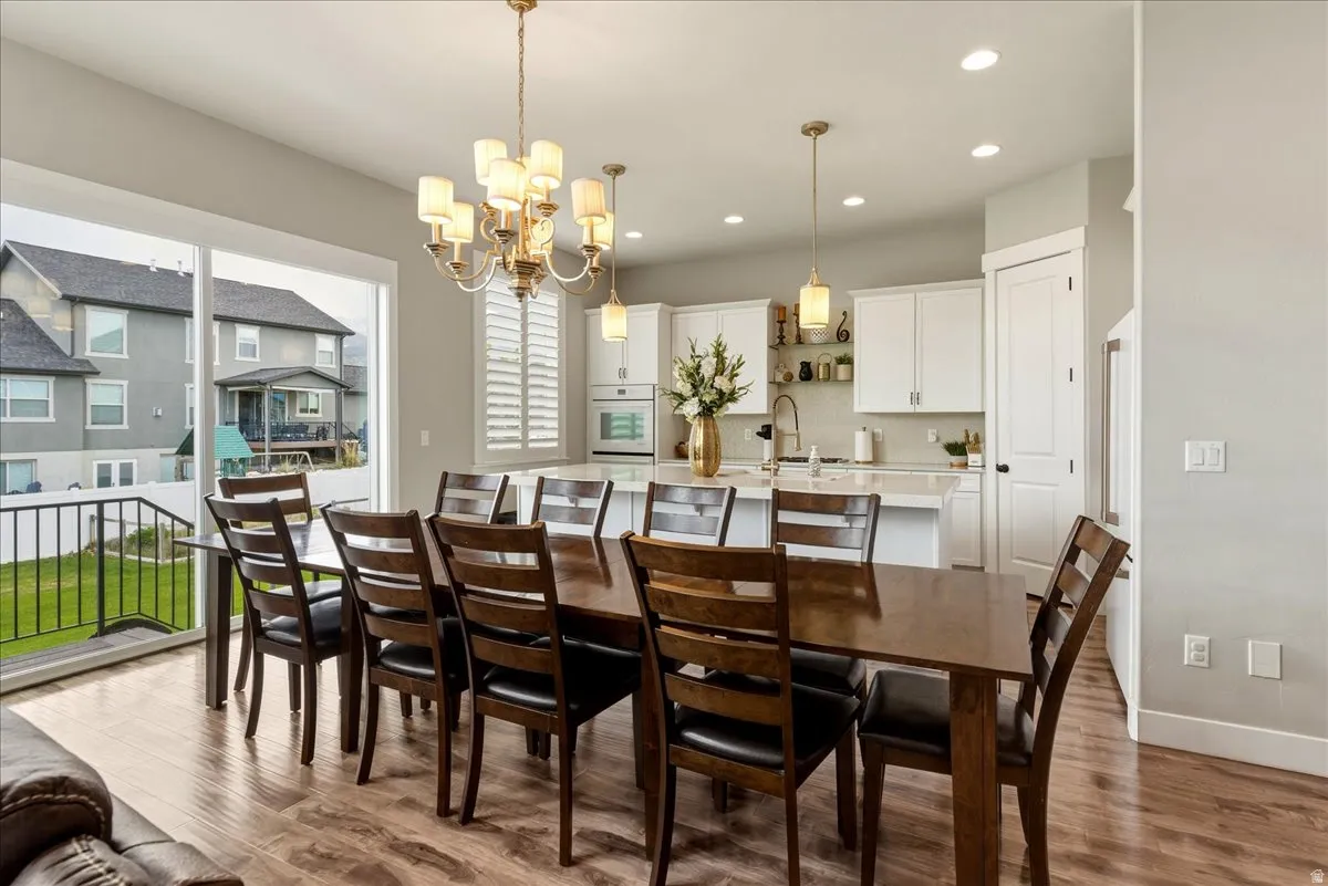 Open-concept living space with wood-finish flooring, a contemporary chandelier, and recessed lighting