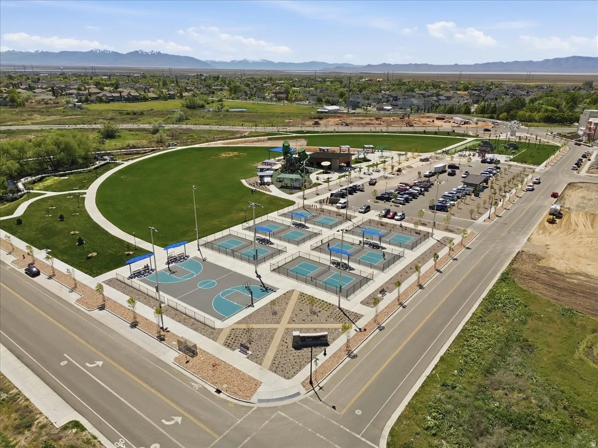 Expansive community park featuring a large green space, multiple sports courts, and a paved walking path