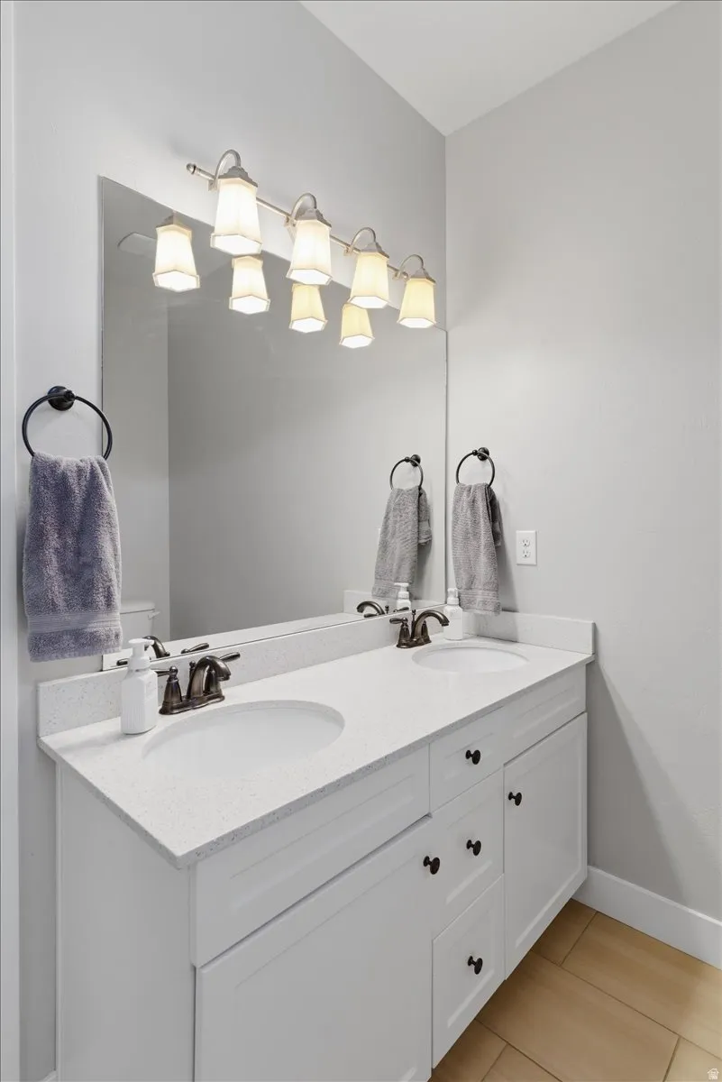Modern bathroom vanity featuring a white quartz countertop, soft-close cabinetry with black hardware, and an undermount sink