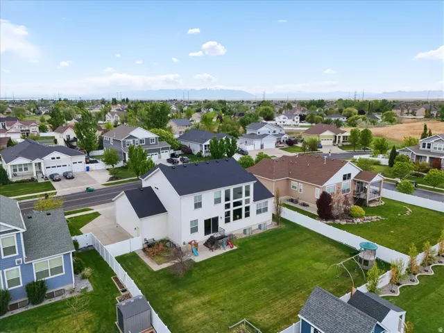 Expansive backyard featuring a manicured lawn, white privacy fencing, and mature landscaping