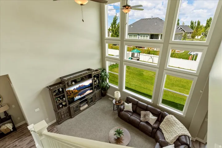 Two-story living area with large-format windows, vaulted ceiling, and ceiling fan