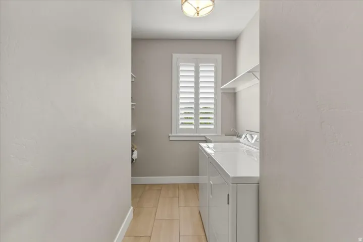 Laundry area with wood-finish flooring, white window shutters, wall-mounted shelving, and a semi-flush ceiling light