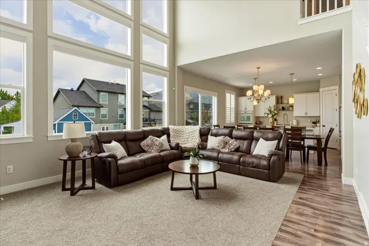 Two-story living area with expansive floor-to-ceiling windows, open-concept design, and wood-finish flooring