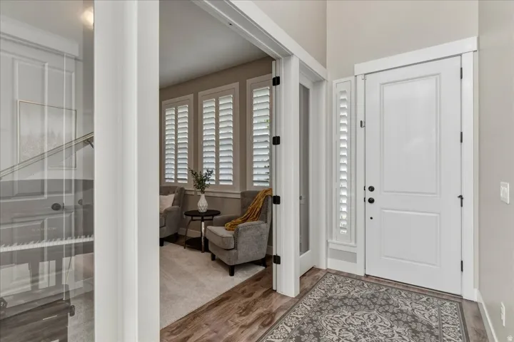 Entryway featuring a white paneled door, coordinating sidelight with plantation shutters, wood-finish flooring, and a glass-paneled interior door