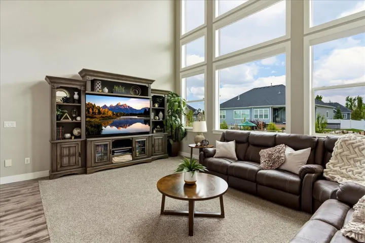 Two-story wall of windows, carpeted flooring, wood-finish flooring, and built-in media cabinetry