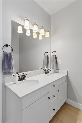 Modern bathroom vanity featuring a white quartz countertop, soft-close cabinetry with black hardware, and an undermount sink