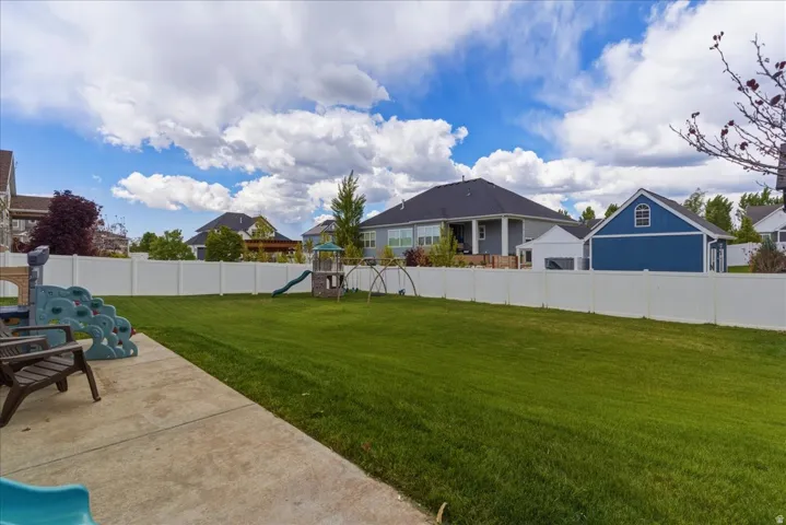 Expansive lawn featuring a concrete patio and full-height privacy fencing