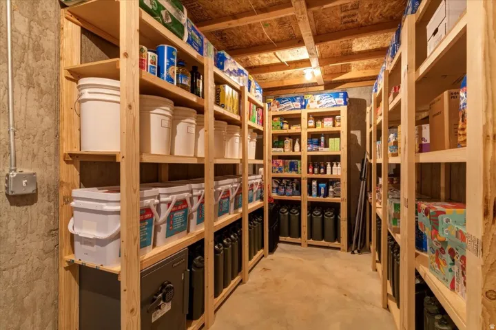 Extensive storage room with multiple rows of wood shelving, exposed ceiling joists, and a concrete floor