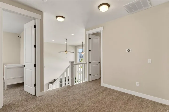 Carpeted landing with white balusters, overhead lighting, and interior doors with black hardware