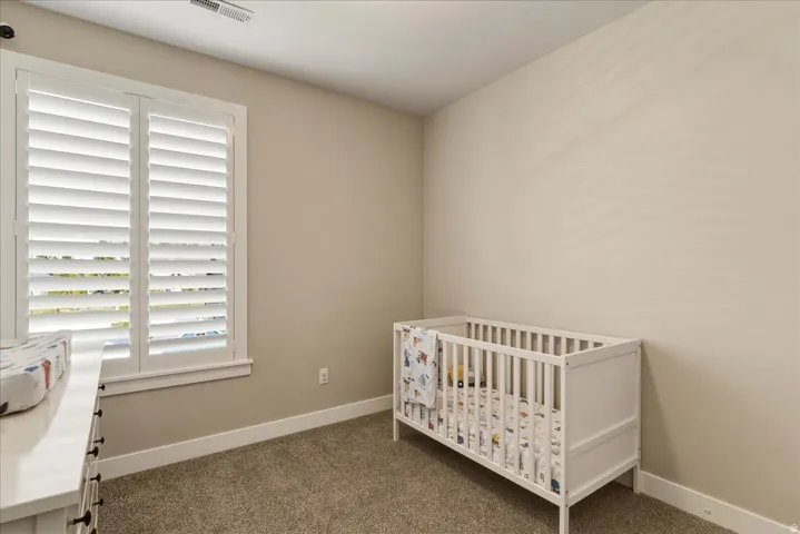 Window with white plantation shutters, neutral tone walls, and carpeted flooring
