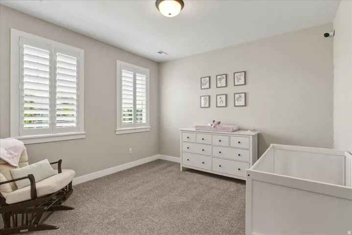 Planted shutters on two windows, recessed ceiling light fixture, neutral wall color, and carpeted flooring