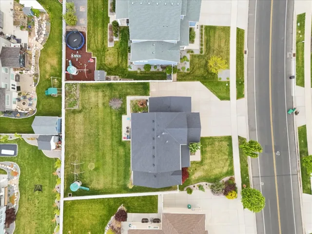 Expansive property featuring a dark-shingle roof, concrete driveway, and a large grassy yard