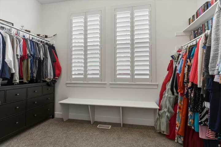 Built-in shelving, white plantation shutters, white window trim, built-in white bench, and carpeted flooring