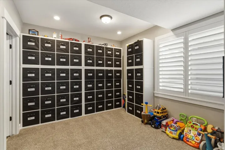 Built-in modular shelving, neutral carpet flooring, recessed lighting, and plantation shutters