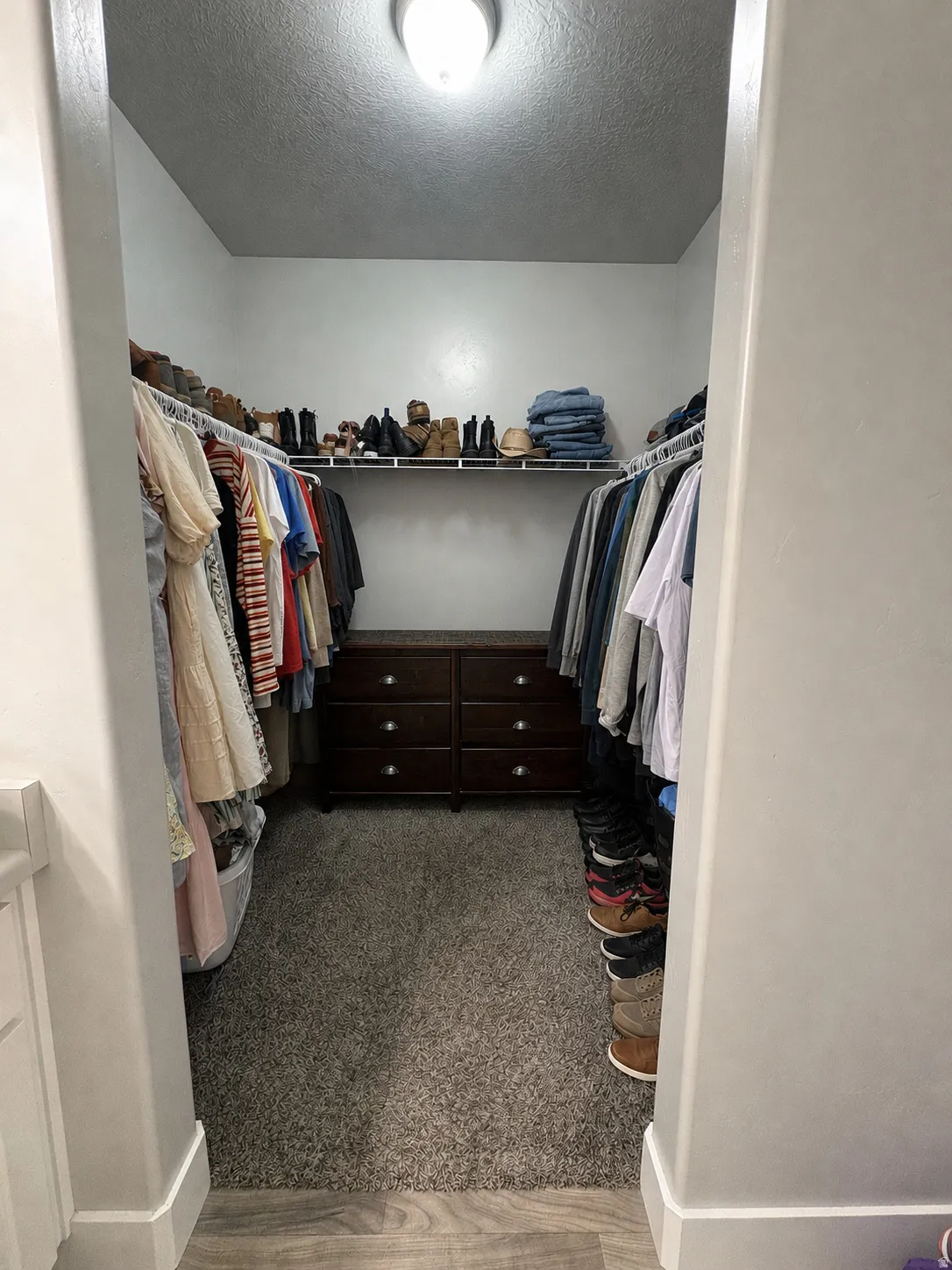 Walk-in closet with built-in shelving, hanging rods, and dark wood-finish drawer storage